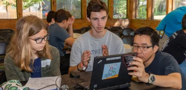 campers with an instructor looking at the laptop